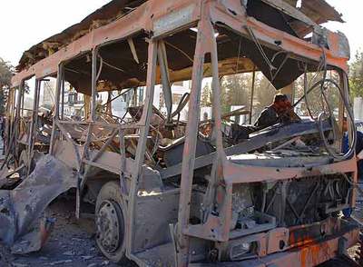 El cadáver del conductor yace dentro de un autobús que llevaba estudiantes camino de la universidad, alcanzado por la primera explosión.