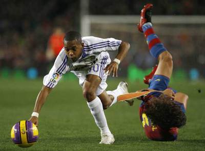 Puyol cae al césped mientras Robinho intenta proseguir la jugada.