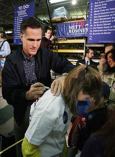 El candidato republicano y ex gobernador de Massachusetts Mitt Romney firma un autógrafo en Grand Rapids.