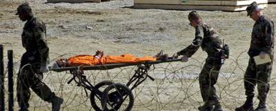 Militares estadounidenses trasladan en camilla a un preso para interrogarlo en la base de Guantánamo en febrero de 2002.