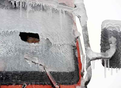 Un conductor trata de ver a través de un agujero  en el parabrisas congelado de su camión, en Guangdong.