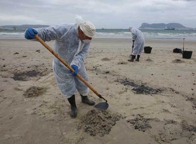 Dos trabajadores del dispositivo desplegado tras el nuevo hundimiento del  New Flame  recogían ayer restos del vertido registrado en la playa El Rinconcillo de Algeciras.