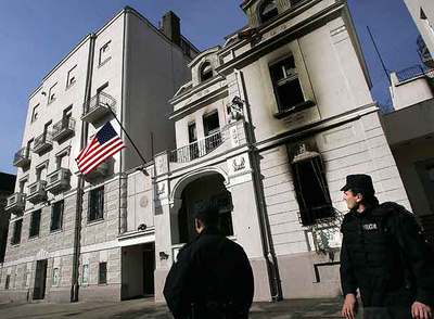 Policías serbios observan la nueva bandera colocada en la Embajada de EE UU en Belgrado.