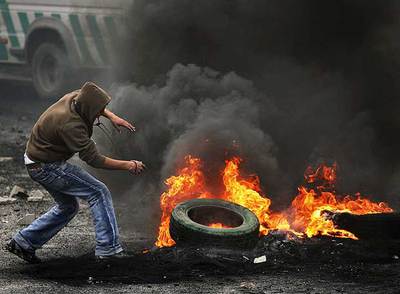 Un palestino aviva el fuego de una barricada en el campo de refugiados de Shuafat, en Cisjordania.