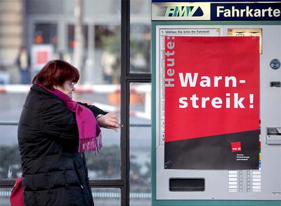 Una mujer ante una máquina expendedora de billetes con un cartel que avisa de la huelga.