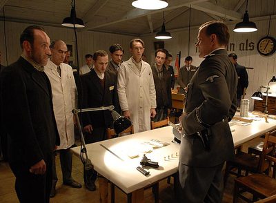 A la izquierda, de negro, Karl Markovics, el protagonista de la película, en el barracón donde preparan los billetes en  Los falsificadores. 