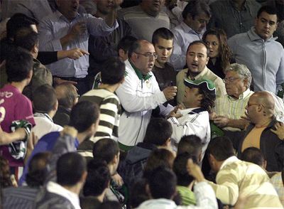 Un hombre sujeta al presunto agresor (con una gorra verde) de Armando.