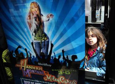 Una niña observa un cartel de la película  Hannah Montana  Miley Cyrus: best of both worlds Concert Tour. 