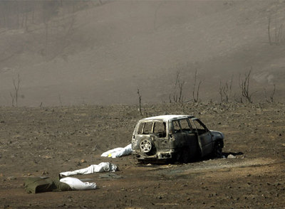 Los cuerpos de tres de los 11 miembros del retén fallecidos en el incendio de Guadalajara yacen junto a su todoterreno el 18 de julio de 2005.