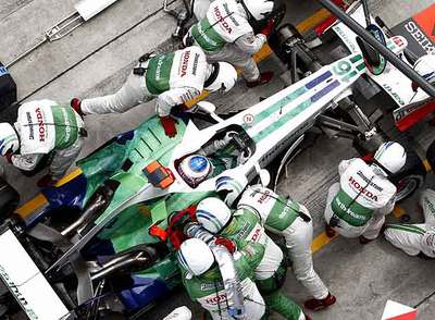 Jenson Button (Honda) recibe la asistencia de sus mecánicos durante el Gran Premio de Malaisia.