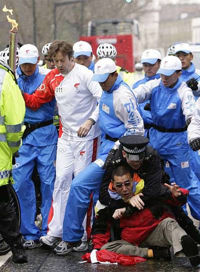Un policía reduce a un manifestante que intentaba acercarse a la antorcha, custodiada por policías chinos.