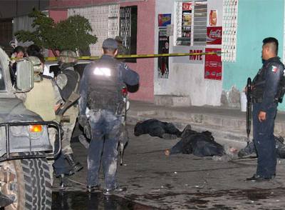 Soldados y policías federales, junto a los cadáveres de tres agentes muertos durante un tiroteo en la ciudad de Culiacán.