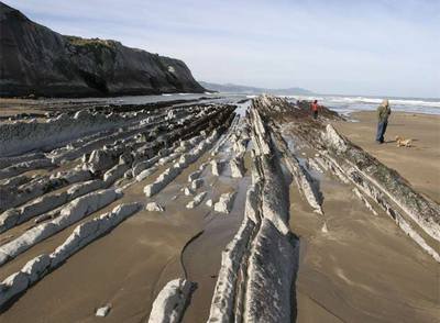 Formaciones rocosas con estratos verticales, conocidas como  flysch,  un milhojas de piedra en la playa de Itzurun, en Zumaia (Guipúzcoa).