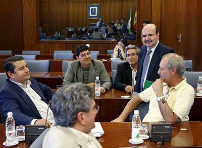Zarrías, de pie, conversa con los representantes políticos antes de comparecer en comisión parlamentaria.