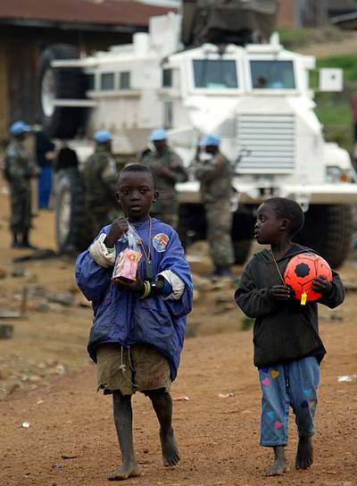 Dos niños pasean ante un grupo de  cascos azules  de la ONU en la ciudad de Kanyabayonga, al este de Congo, en diciembre de 2004.