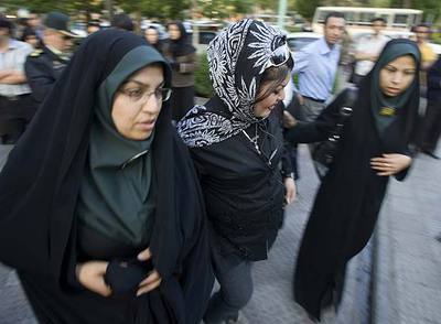 Dos policías escoltan a una joven (centro) hacia una comisaría de Teherán por pintarse y llevar 