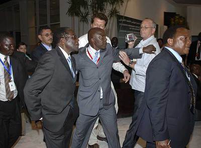 Agentes de seguridad escoltan a Robert Mugabe (a la izquierda y con gafas), ayer en Sharm el Sheij.