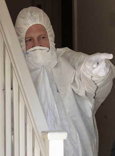 Un policía forense señala el lugar donde se hallaron los cadáveres.