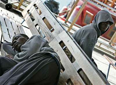 Dos inmigrantes  sin papeles,  llegados ayer en patera a Tenerife, esperan en el puerto de Los Cristianos.