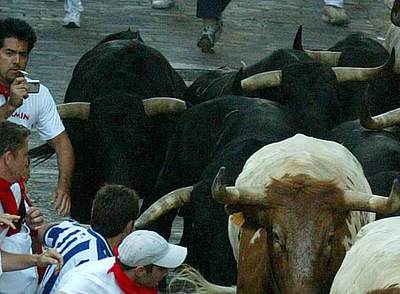 Un mozo, con el pitillo en la boca, la cámara de fotos y un toro detrás, en la cuesta de Santo Domingo durante el encierro de ayer.