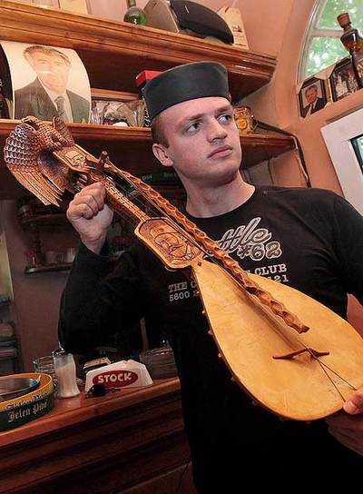 Un hombre muestra, bajo la foto de Radovan Karadzic, el  gusla  del bar Casa Loca, que el detenido hacía sonar.