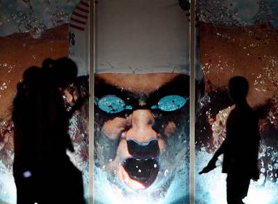 Varios espectadores pasan frente a un cartel con la imagen de Phelps en el Centro Acuático Nacional de Pekín.