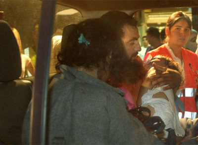 Una mujer y un hombre on un bebé en brazos, salen del polideportivo donde fueron atendidos.