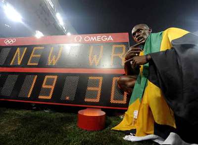 El jamaicano Usain Bolt realiza el mismo gesto con la enseña de su país, tras ganar la final de los 200m en Pekín y rebajar dos centésimas la marca de Johnson.