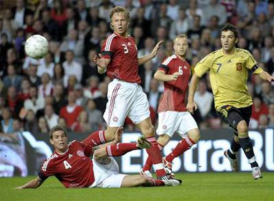 Agger, en el suelo, despeja el balón ante la llegada de Villa.