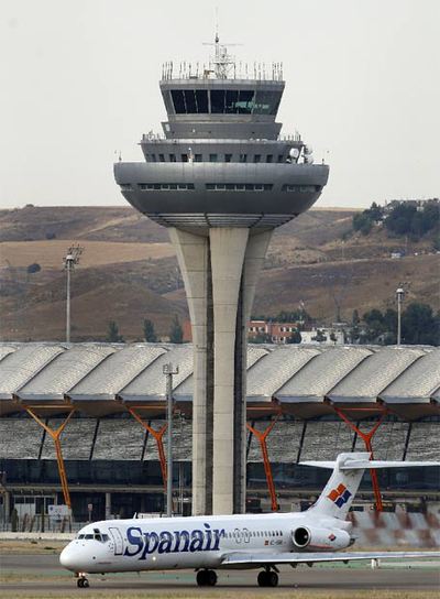 Una nave de Spanair junto a la torre de control de Barajas.