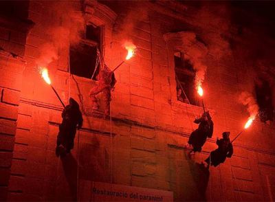 Uns 'diables' trepan por una fachada en un momento del Aquelarre de Cervera.