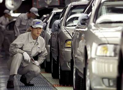 Un técnico surcoreano inspecciona un coche en una cadena de montaje en Pusán, Corea del Sur.