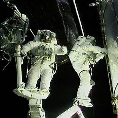 Dos astronautas trabajan en la puerta del telescopio  Hubble,  durante una misión de servicio del mismo.