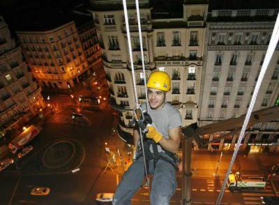 Operarios especializados en trabajo vertical  rappelan  por la fachada del edificio Telefónica para colgar la obra de Lang y Bauman  Comfort # 6. 