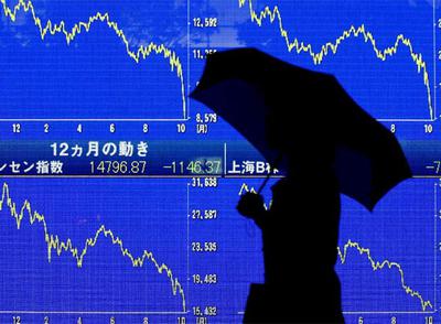 Una mujer pasa frente a un panel que muestra el descalabro de los valores de la Bolsa de Tokio.