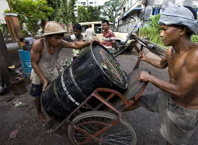 Dos trabajadores acarrean un barril de petróleo procedente del mercado negro, el pasado martes en Rangún (Birmania).