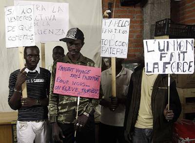 Un grupo de  manteros  muestra las pancartas con las que se manifestarán hoy por el indulto de Mor, el último por la derecha. En la del centro se lee en francés: 