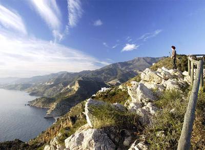 Una joven observa el Paraje Natural Acantilados de Maro-Cerro Gordo, en la frontera sur de Málaga y Granada.