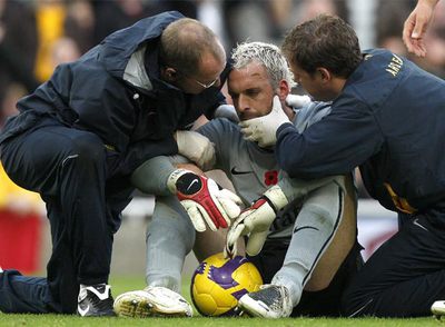 Almunia, conmocionado, es atendido por los asistentes del Arsenal.