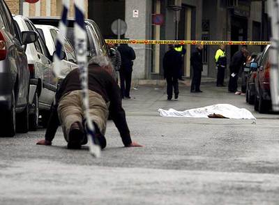 Un agente judicial busca casquillos cerca del lugar en el que yace el cadáver de uno de los atracadores.