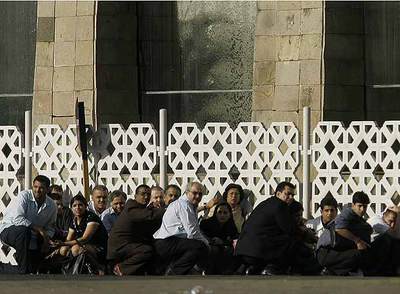 Varias personas se ponen a cubierto durante un tiroteo en el exterior del hotel Taj Mahal de Bombay.