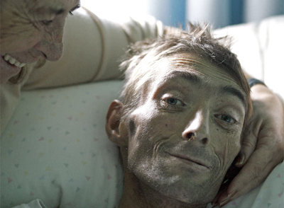 María José, que ha visto morir a cuatro de sus nueve hijos, acaricia a José,  El Tete,  enfermo de sida.