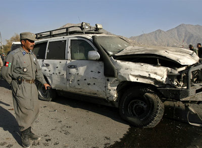 Un policía afgano, junto  al vehículo de la Embajada alemana atacado por un terrorista en Kabul.