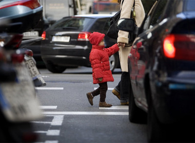 Una niña pasa a la altura de los tubos de escape de los coches, en una calle de Barcelona.
