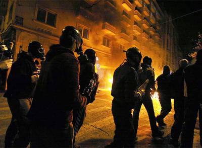 Manifestantes griegos, con máscaras antigás y armados con  cócteles molotov,  se dirigen hacia la policía anoche en el centro de Atenas.