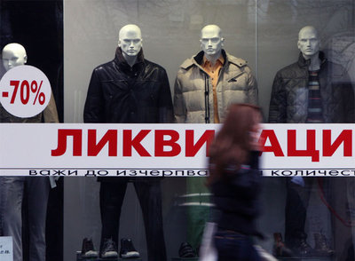Una joven camina por delante de un escaparate con grandes rebajas en una calle del centro de Sofía.