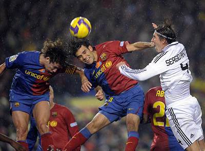 Puyol y Márquez despejan el balón ante Sergio Ramos.