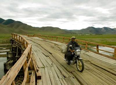 Un motorista cruza el río Ider por el destartalado puente de Jargalant, en el centro de Mongolia.