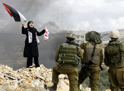 Una joven palestina se manifiesta frente a  tres soldados israelíes en la localidad de Bilin, cercana a Ramala, en Cisjordania, durante una protesta contra la ofensiva en Gaza.