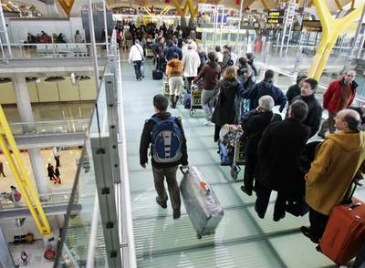 Decenas de pasajeros hacen cola ayer en los accesos a la T-4 del aeropuerto de Barajas.